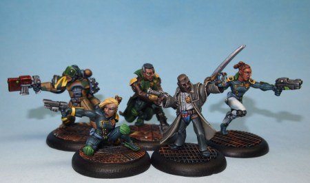 Photo of five painted futuristic law enforcement miniatures on a blue background.